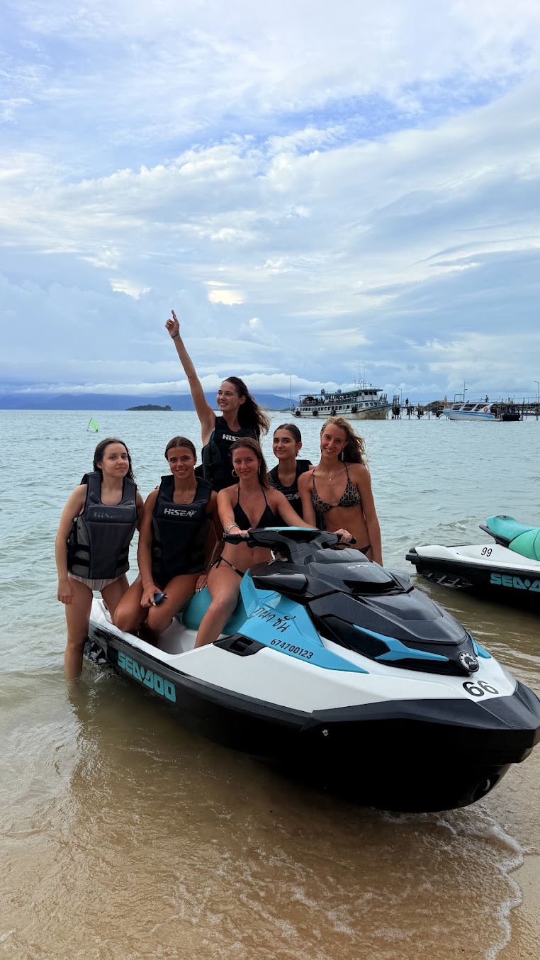 Friends celebrating on Sea-Doo jet skis at the shoreline in Koh Samui
